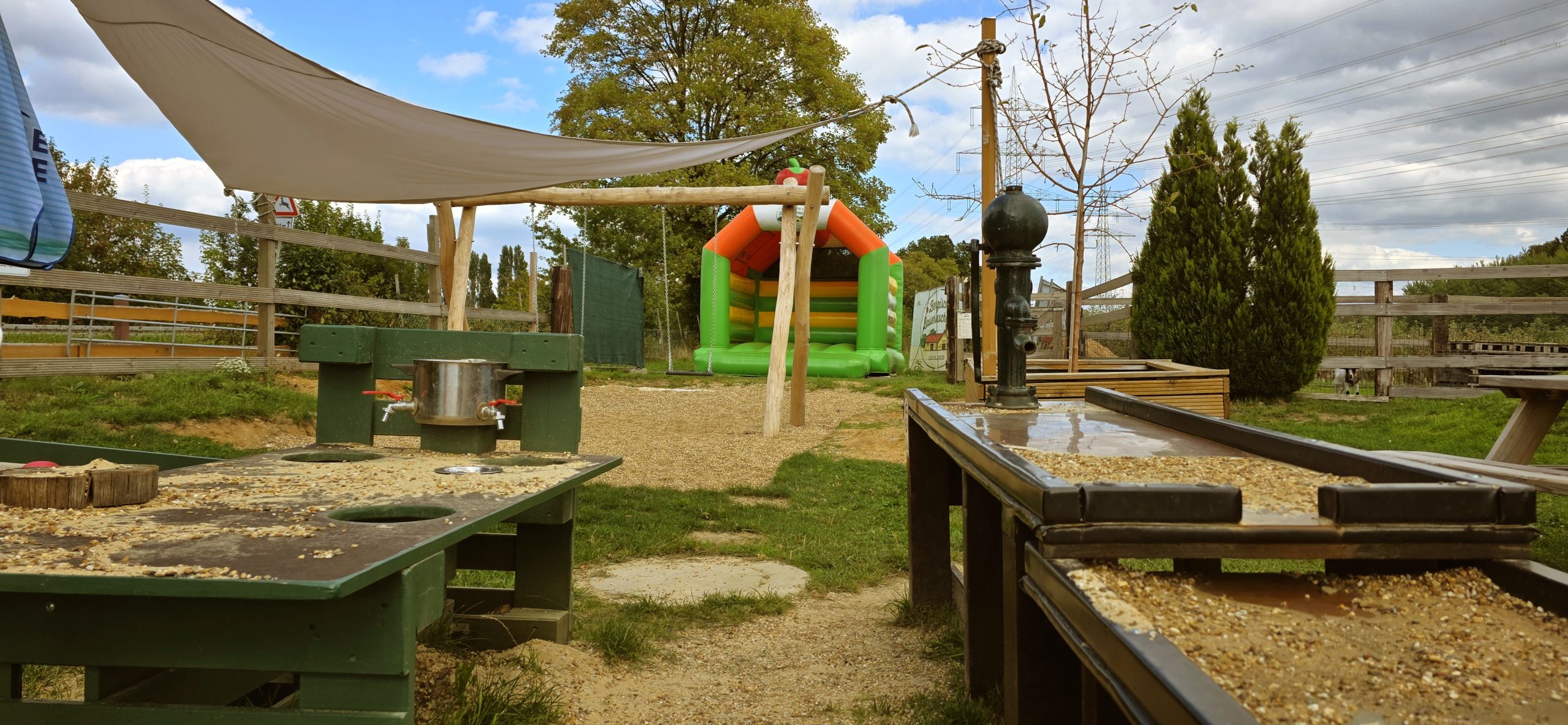 Matschküche mit Wasserpumpe und Hüpfburg im Spielbereich der Bergischen Bauernscheune